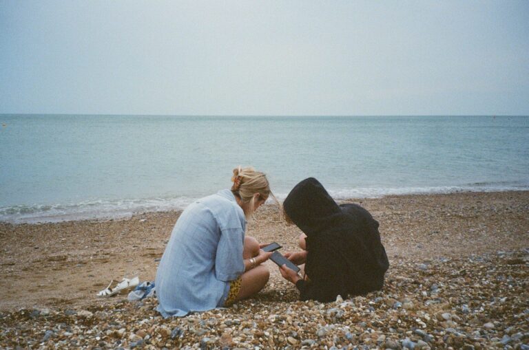 A couple of people sitting on top of a beach